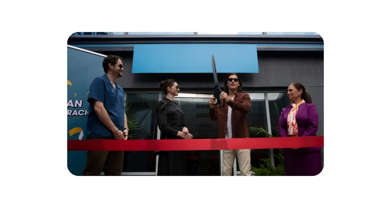 un homme coupe le ruban devant deux femmes et un autre homme